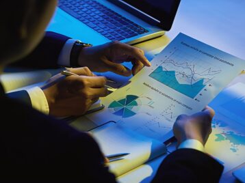 Business professionals reviewing analytics reports and charts to assess B2B data lifecycle management and identify where data loses value over time