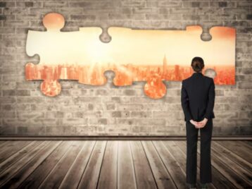 Business professional looking at interlocking puzzle pieces symbolizing M&A data integration and the challenge of aligning systems, data, and RevOps after a merger.