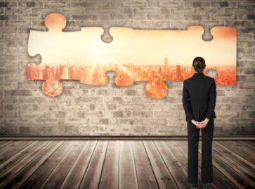 Business professional looking at interlocking puzzle pieces symbolizing M&A data integration and the challenge of aligning systems, data, and RevOps after a merger.