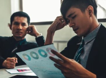 Business professionals reviewing complex performance reports, highlighting how distributed intelligence RevOps can reduce analytics bottlenecks and accelerate GTM decisions.
